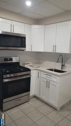 a kitchen with granite countertop a sink dishwasher a stove and a microwave oven with cabinets