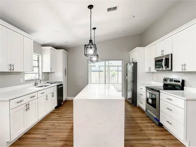 a large kitchen with kitchen island granite countertop a sink a stove top oven a counter space and cabinets