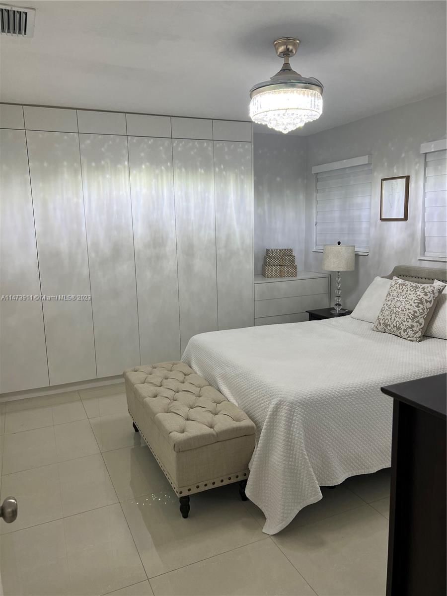 4610 Southwest 89th Place Miami, FL 33165 - Photo 38 of 52 a bedroom with a bed and a chandelier