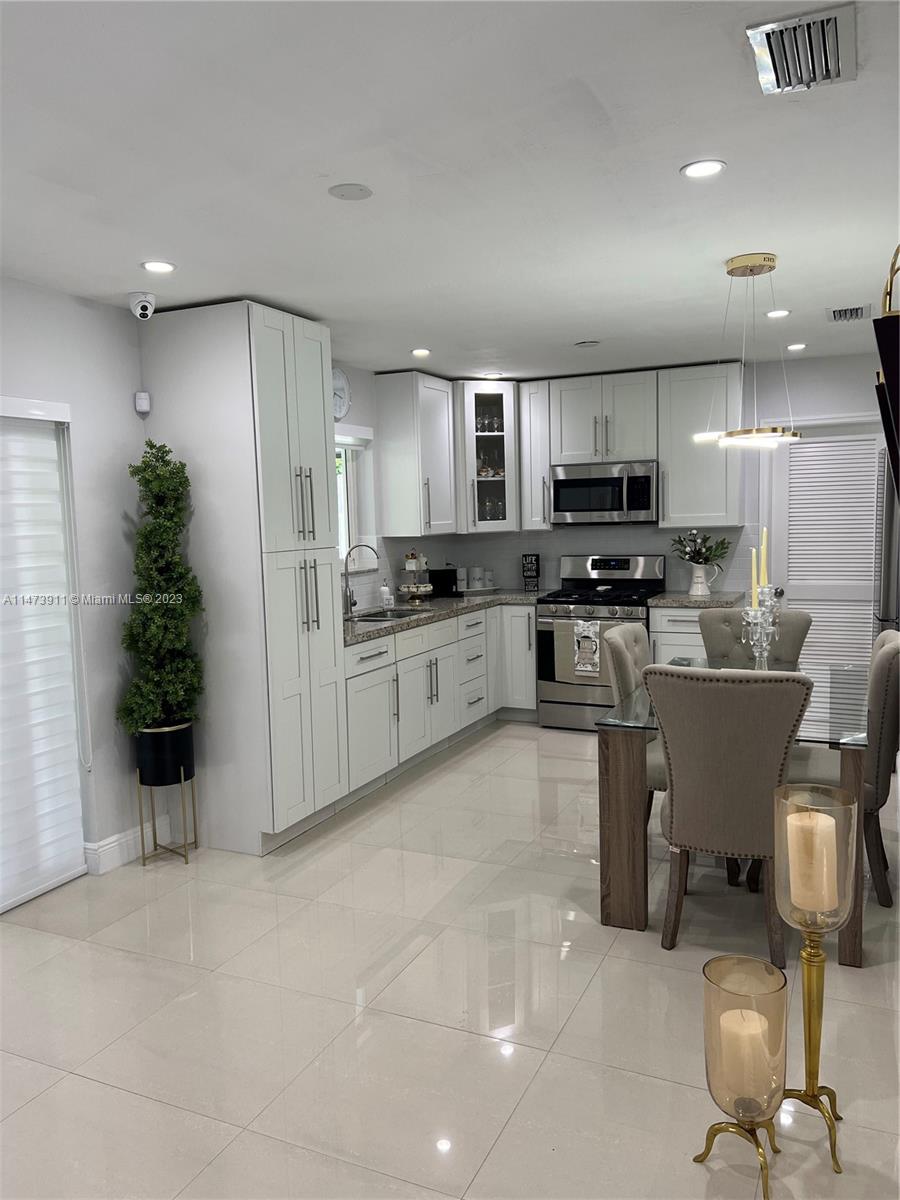 4610 Southwest 89th Place Miami, FL 33165 - Photo 43 of 52 a kitchen with stainless steel appliances a stove a sink a microwave a refrigerator and cabinets