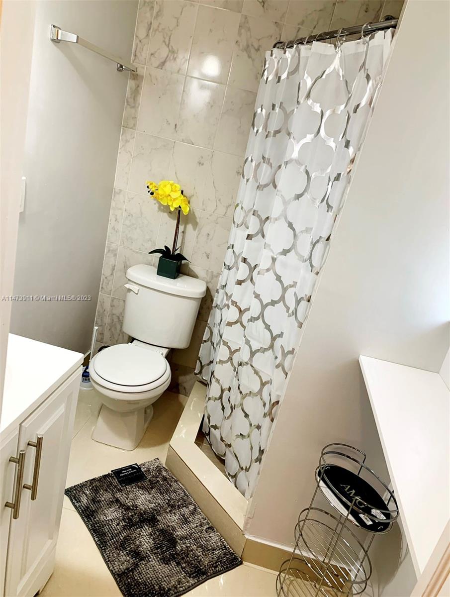 4610 Southwest 89th Place Miami, FL 33165 - Photo 47 of 52 a bathroom with a toilet and a shower curtain