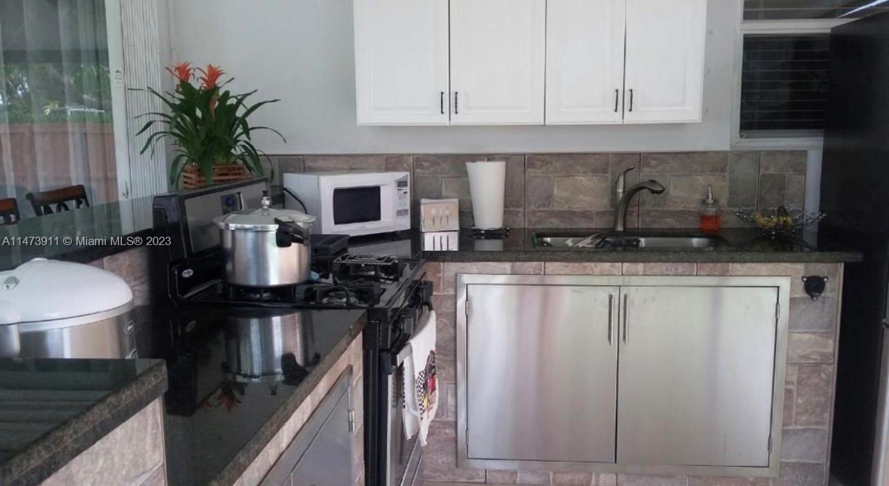 4610 Southwest 89th Place Miami, FL 33165 - Photo 48 of 52 a kitchen with stainless steel appliances granite countertop a refrigerator a stove a sink a dining table and chairs