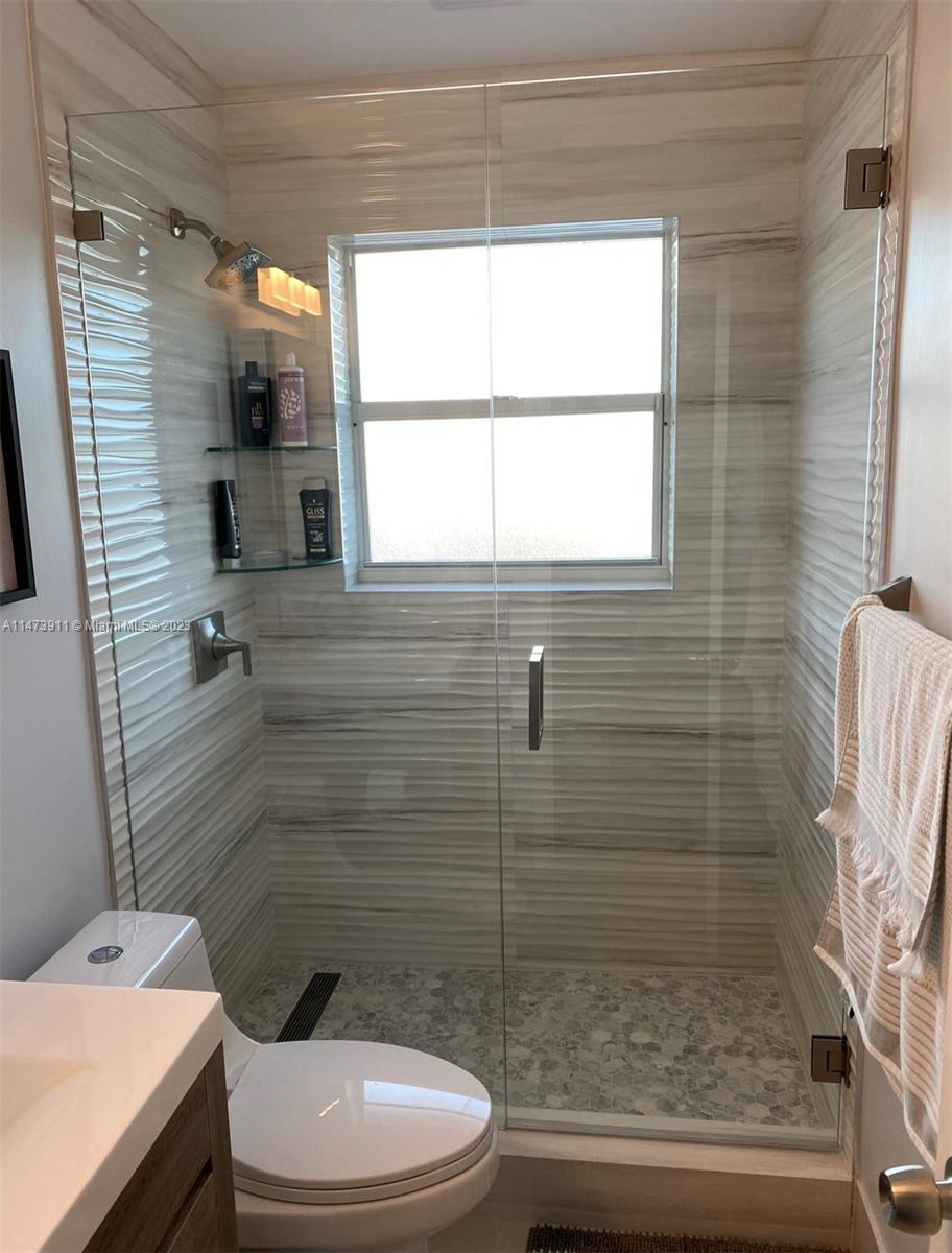4610 Southwest 89th Place Miami, FL 33165 - Photo 51 of 52 a bathroom with a toilet a sink a shower and a window