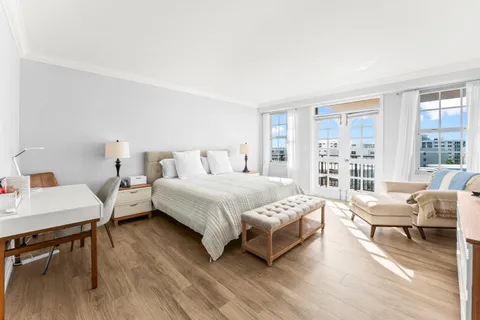 a spacious bedroom with a bed a table chair and a large window