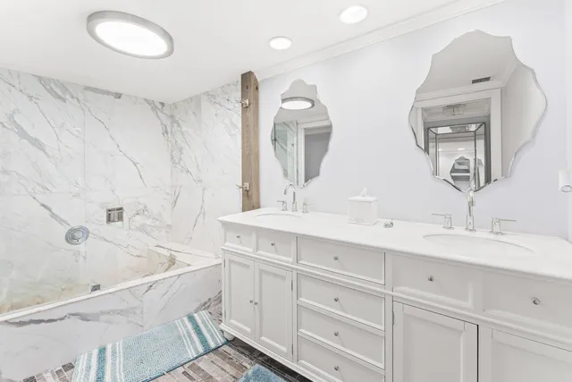 a bathroom with a double vanity sink mirror and bathtub