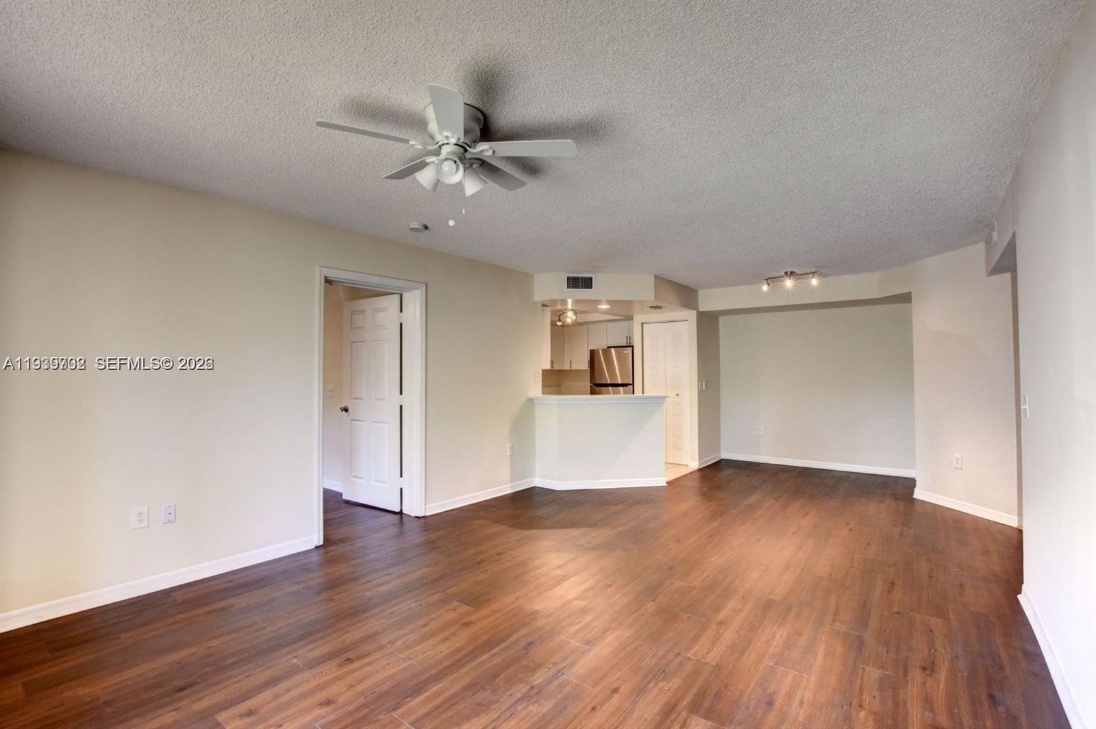 4159 Haverhill Road, Unit 1302 West Palm Beach, FL 33417 - Photo 11 of 19 a view of an empty room with wooden floor and a ceiling fan