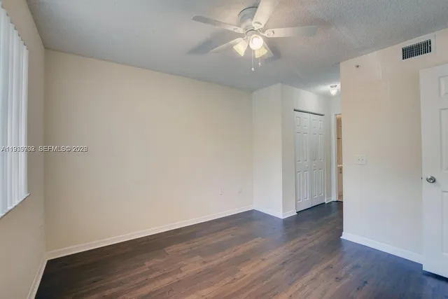 an empty room with wooden floor and fan