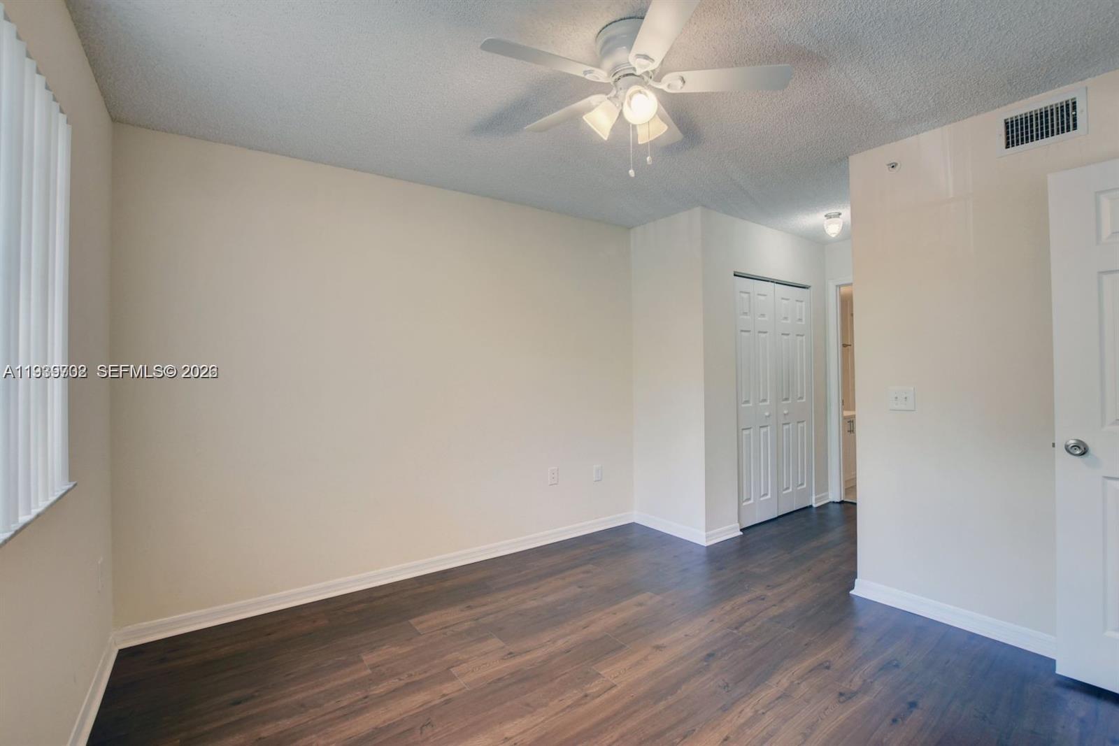 4159 Haverhill Road, Unit 1302 West Palm Beach, FL 33417 - Photo 12 of 19 an empty room with wooden floor and fan