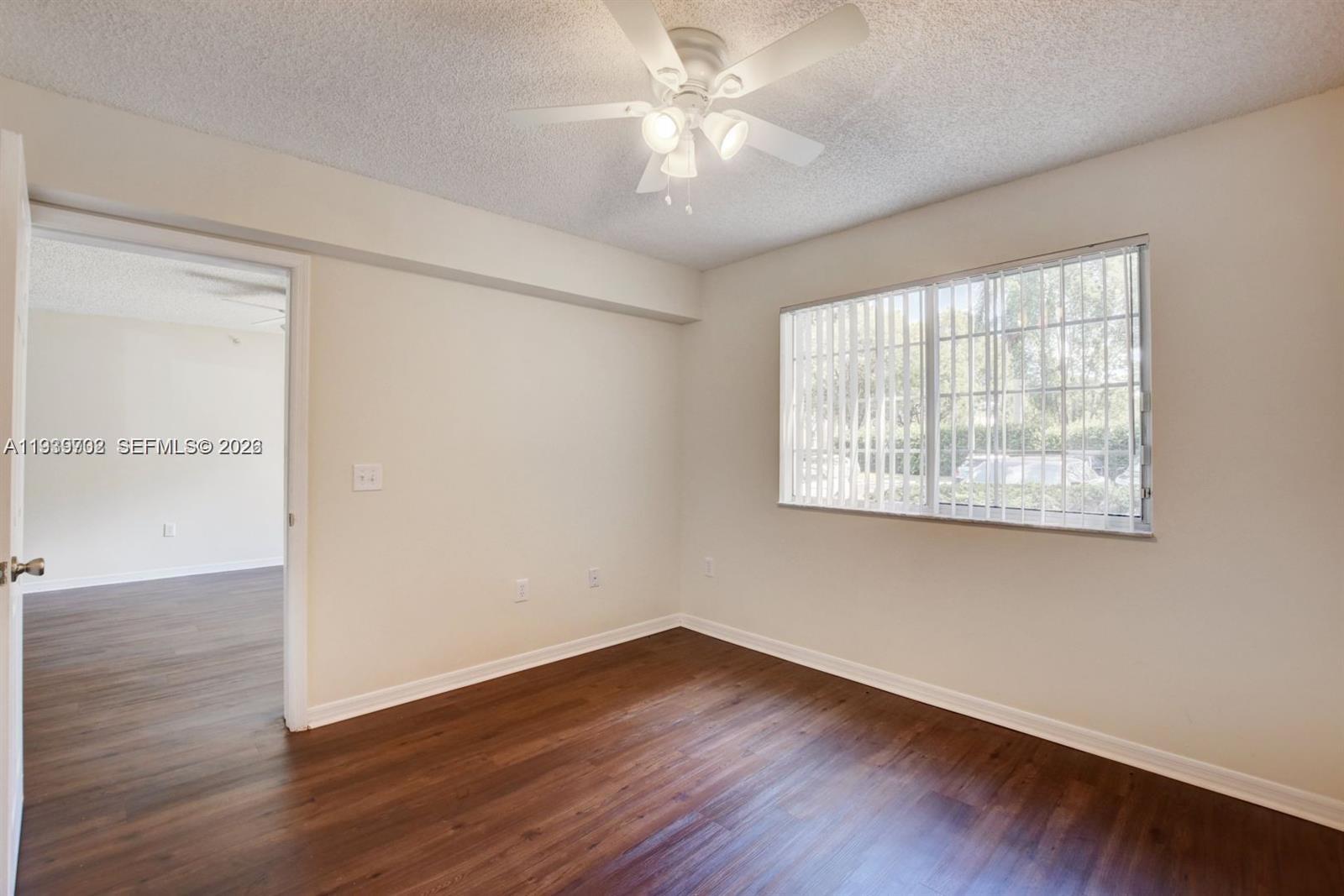 4159 Haverhill Road, Unit 1302 West Palm Beach, FL 33417 - Photo 13 of 19 an empty room with wooden floor and windows