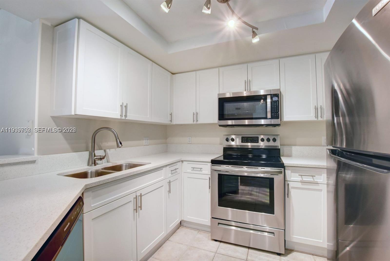 4159 Haverhill Road, Unit 1302 West Palm Beach, FL 33417 - Photo 2 of 19 a kitchen with white cabinets stainless steel appliances and sink