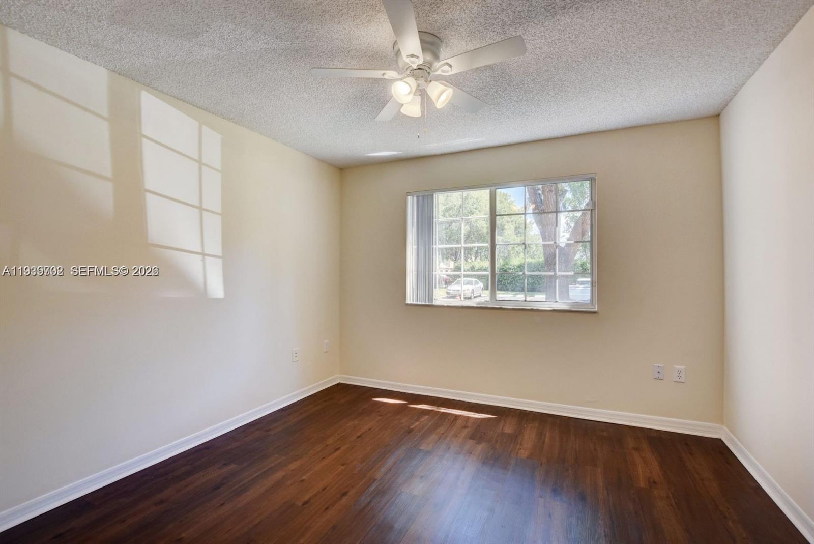 4159 Haverhill Road, Unit 1302 West Palm Beach, FL 33417 - Photo 7 of 19 an empty room with wooden floor chandelier fan and windows