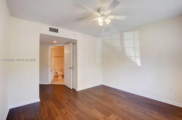 an empty room with wooden floor closet and windows