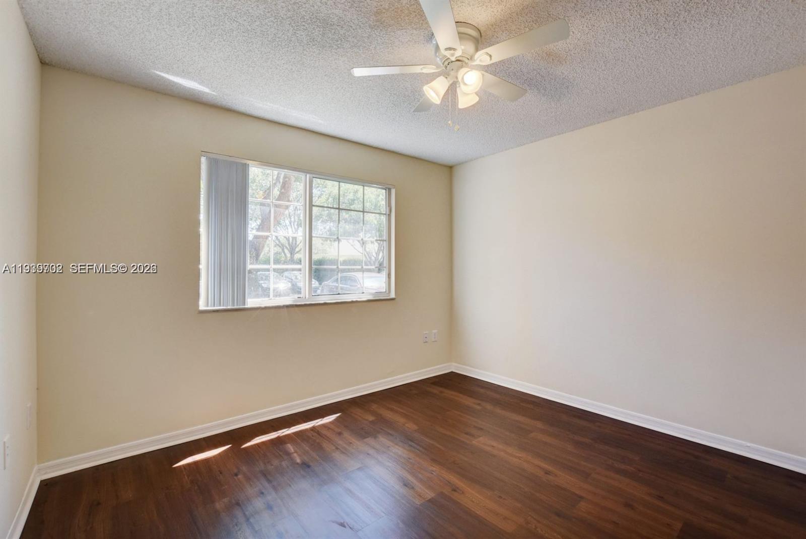 4159 Haverhill Road, Unit 1302 West Palm Beach, FL 33417 - Photo 10 of 19 an empty room with wooden floor fan and windows