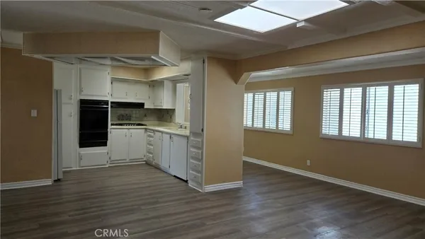 a kitchen with cabinets wooden floor and stainless steel appliances
