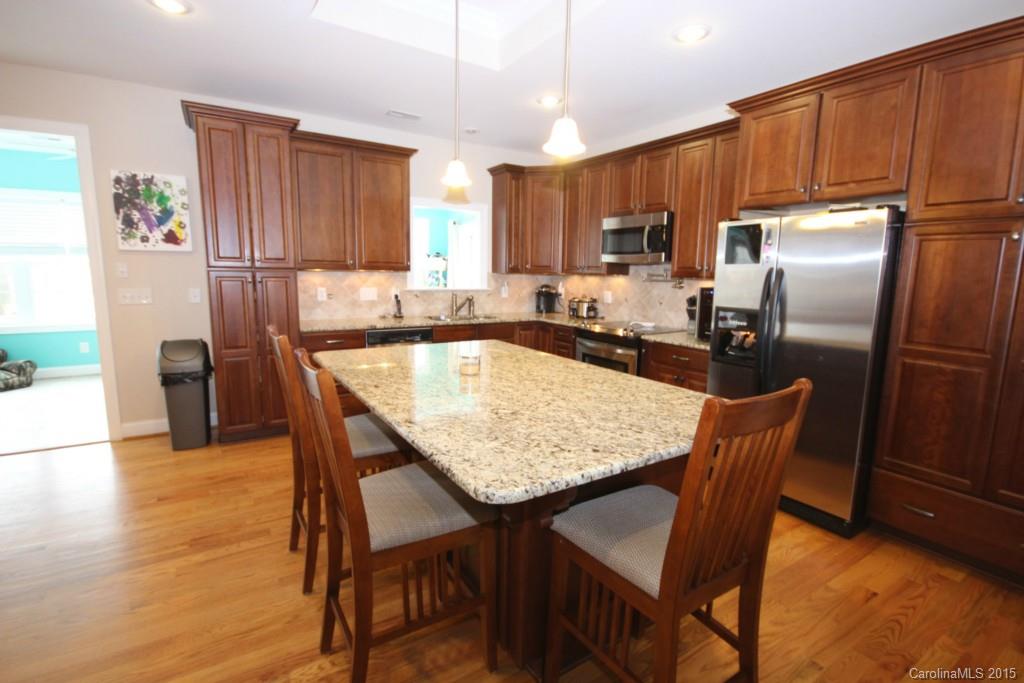 1659 Pine Bluff Court Fort Mill, SC 29708 - Photo 6 of 16 a kitchen with granite countertop a table chairs stainless steel appliances and wooden cabinets
