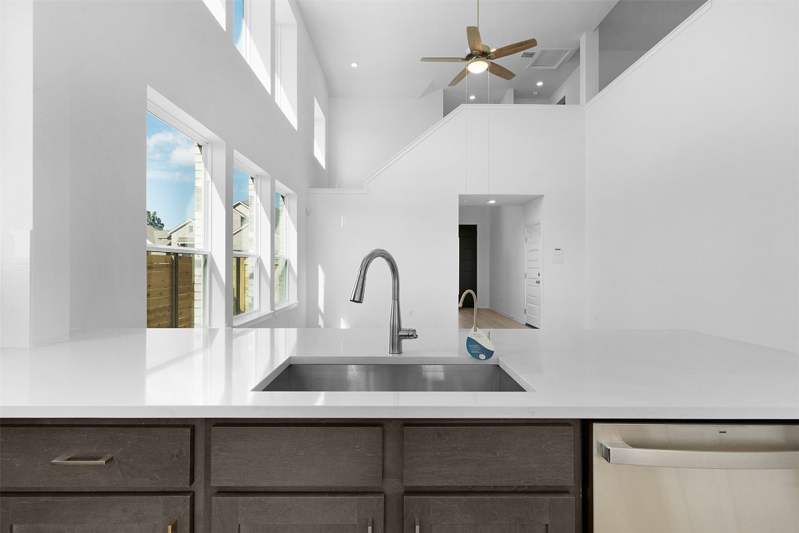 417 Raleigh Drive Georgetown, TX 78633 - Photo 6 of 29 Kitchen with stainless steel dishwasher, light stone counters, a ceiling fan, and a towering ceiling