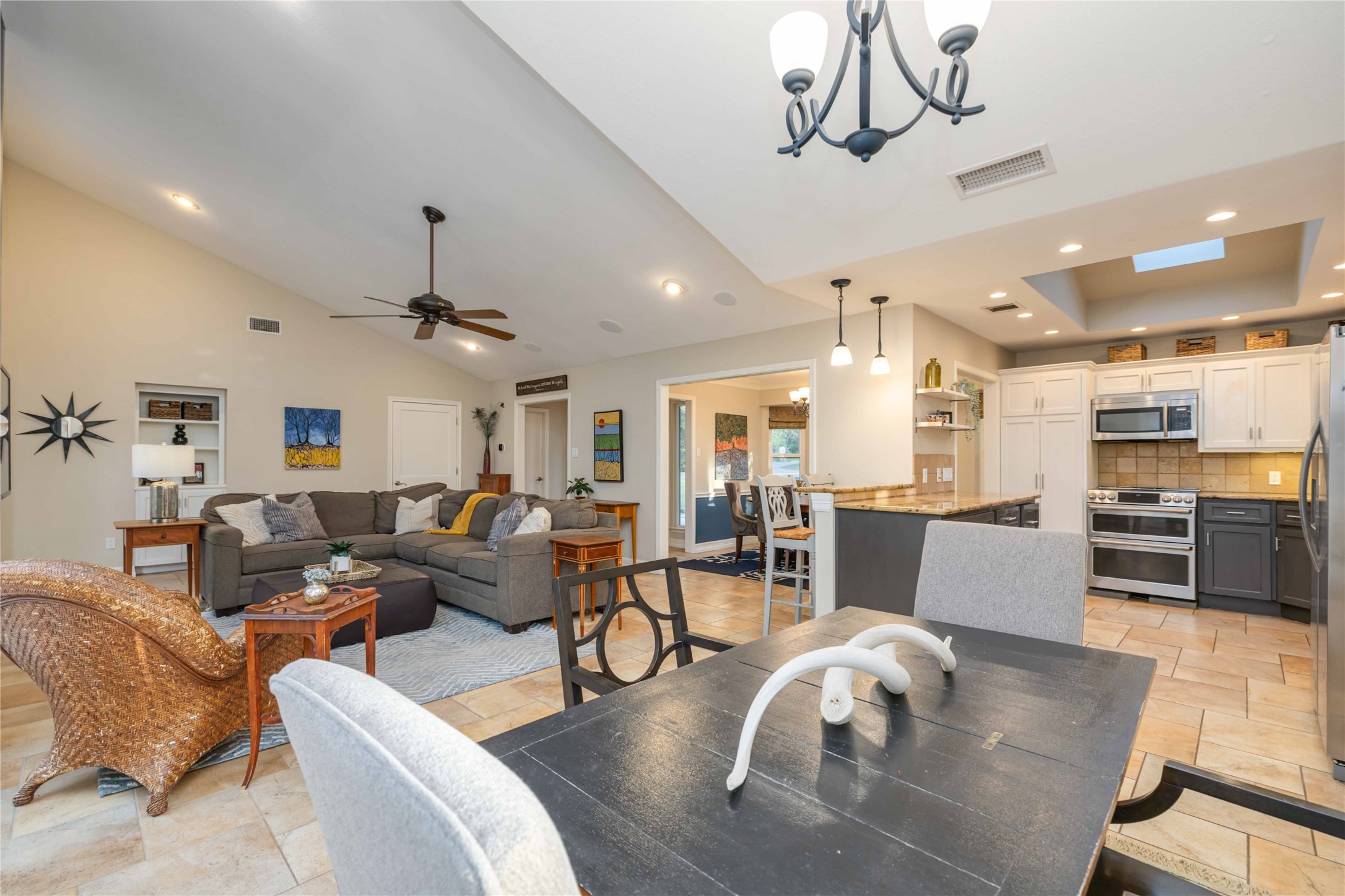 10903 Cade Circle Austin, TX 78726 - Photo 19 of 40 Dining room featuring stone tile flooring, a chandelier, ceiling fan, a high ceiling, and a skylight