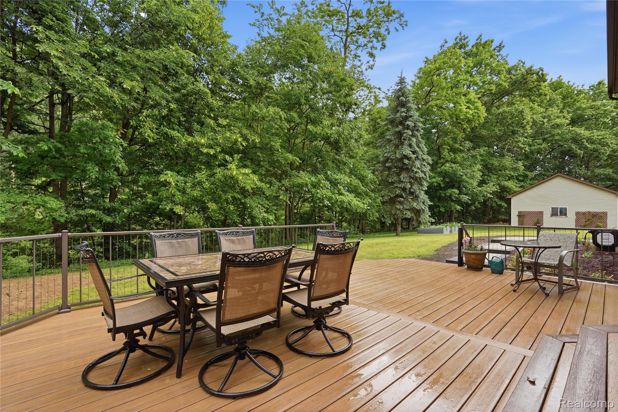 68345 Romeo Plank Road Ray, MI 48096 - Photo 5 of 52 Expansive outdoor deck featuring wood-finish flooring, a metal railing, and a verdant backdrop of mature trees