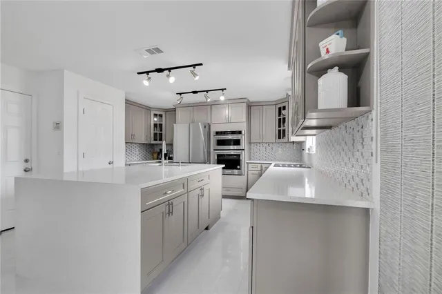 a kitchen with stainless steel appliances granite countertop a sink and dishwasher a refrigerator with white cabinets