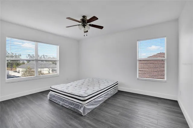 a view of a room with a hardwood floor ceiling fan and windows