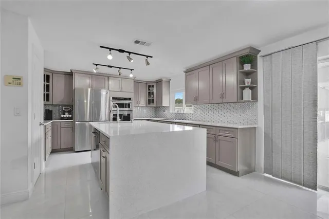 a kitchen with kitchen island white cabinets and stainless steel appliances