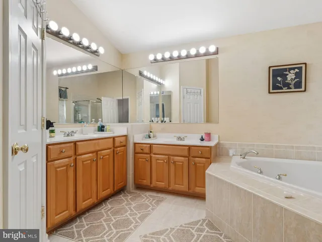 a spacious bathroom with a bathtub a double vanity sink and a mirror
