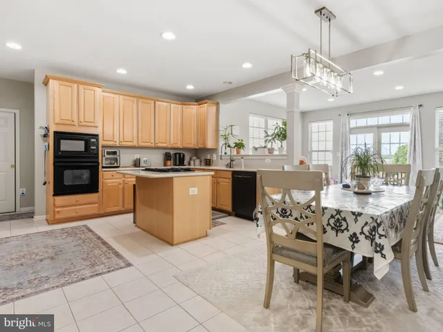 a kitchen with stainless steel appliances granite countertop a stove top oven a sink dishwasher a dining table and chairs with wooden floor