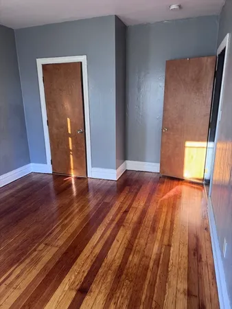an empty room with wooden floor and entrance