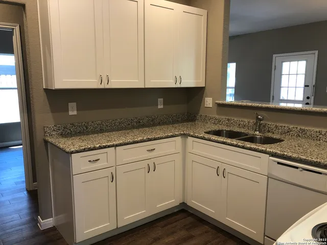 a kitchen with granite countertop white cabinets and sink