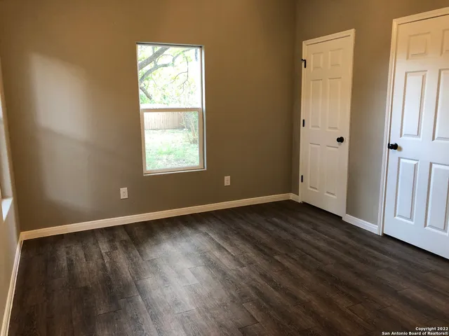 a view of a backyard with large trees and wooden fence