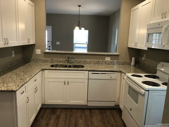a kitchen with granite countertop a sink stove and cabinets