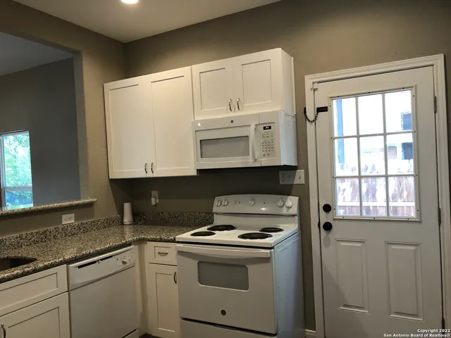 a kitchen with granite countertop white cabinets and white appliances