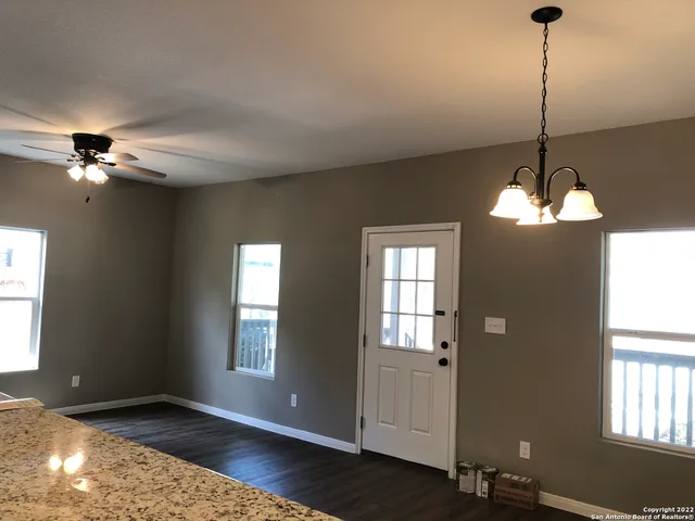 a view of an empty room with window and wooden floor