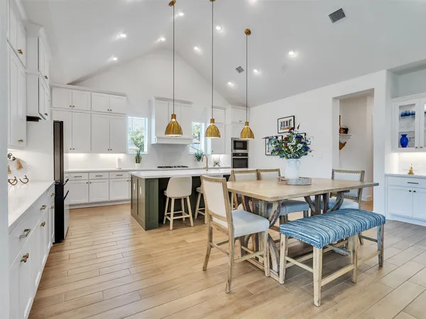 a kitchen with stainless steel appliances kitchen island granite countertop a table chairs sink and cabinets