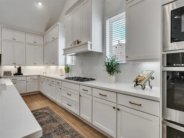 a kitchen with cabinets stainless steel appliances a sink and potted plant