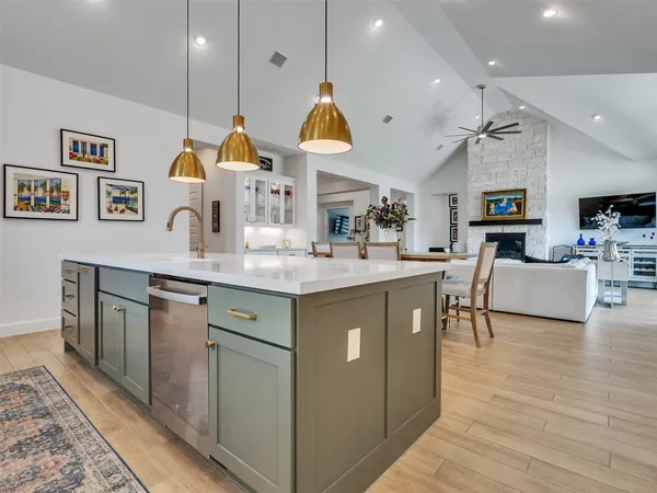 a kitchen with kitchen island granite countertop a sink a stove and a wooden floors