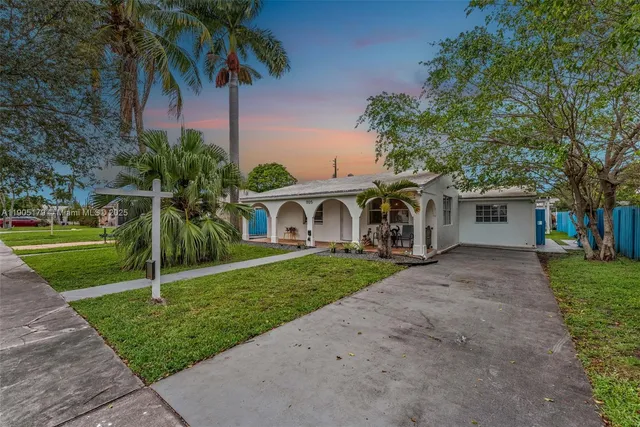 a view of a house with a yard and palm trees