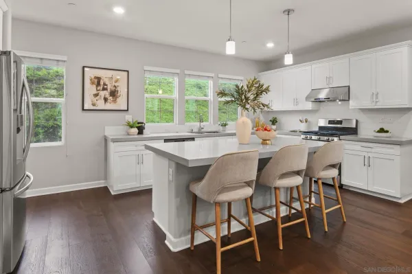 a kitchen with stainless steel appliances granite countertop a stove a refrigerator a sink dishwasher a dining table and chairs with wooden floor
