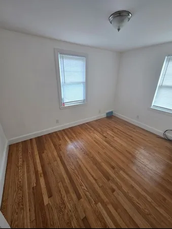 an empty room with wooden floor cabinet and windows