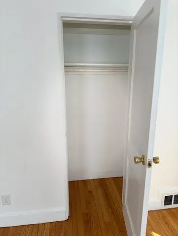 a view of an empty room with wooden floor and closet