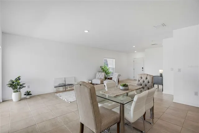 a kitchen with a refrigerator a stove a sink a dining table and chairs