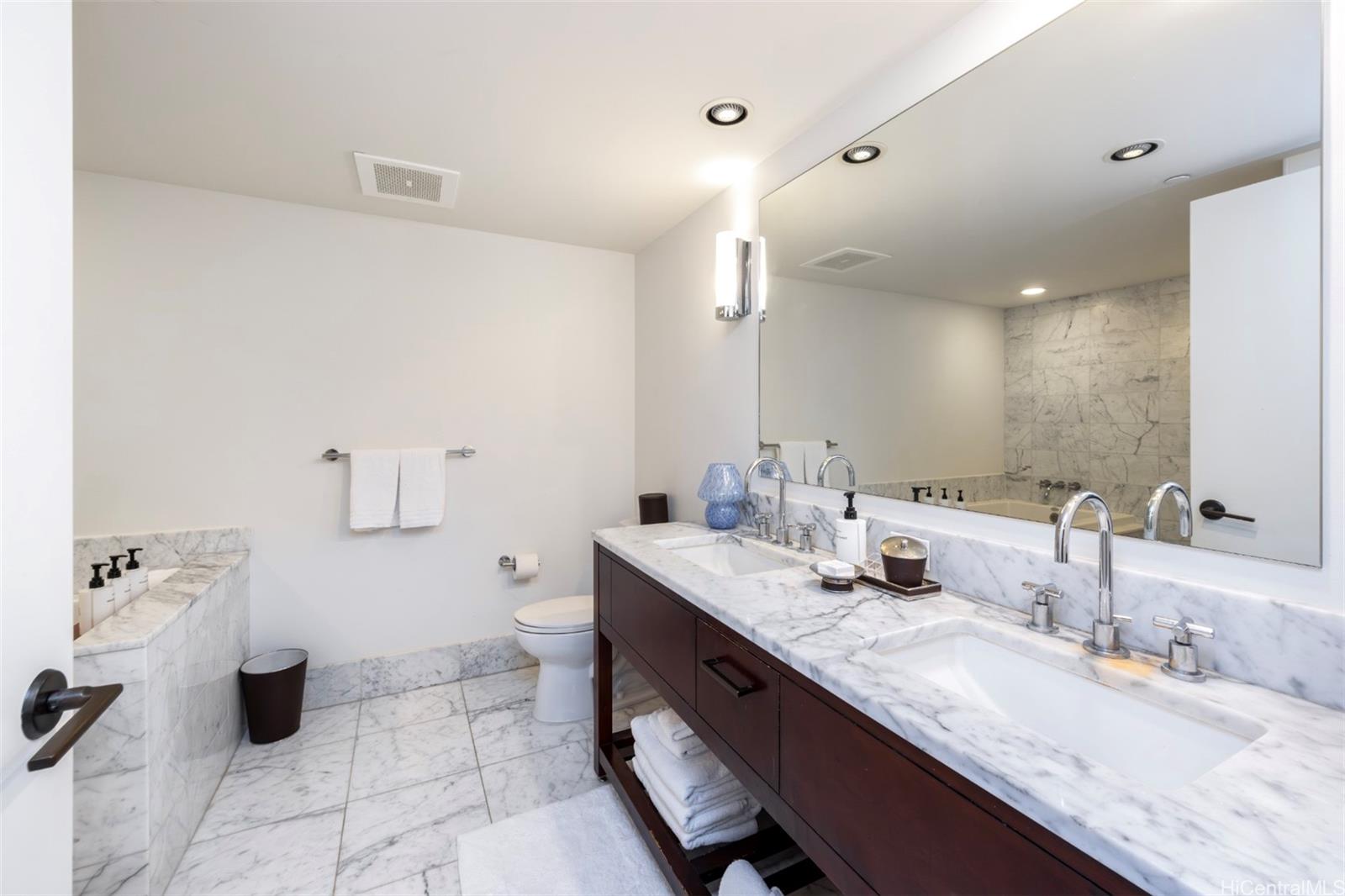 223 Saratoga Road, Unit 810 Honolulu, HI 96815 - Photo 12 of 24 a bathroom with a granite countertop sink a toilet and a mirror