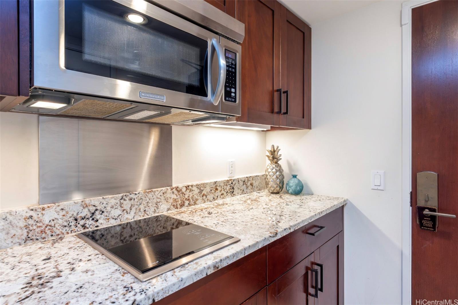 223 Saratoga Road, Unit 810 Honolulu, HI 96815 - Photo 10 of 24 a kitchen with granite countertop a sink and a microwave