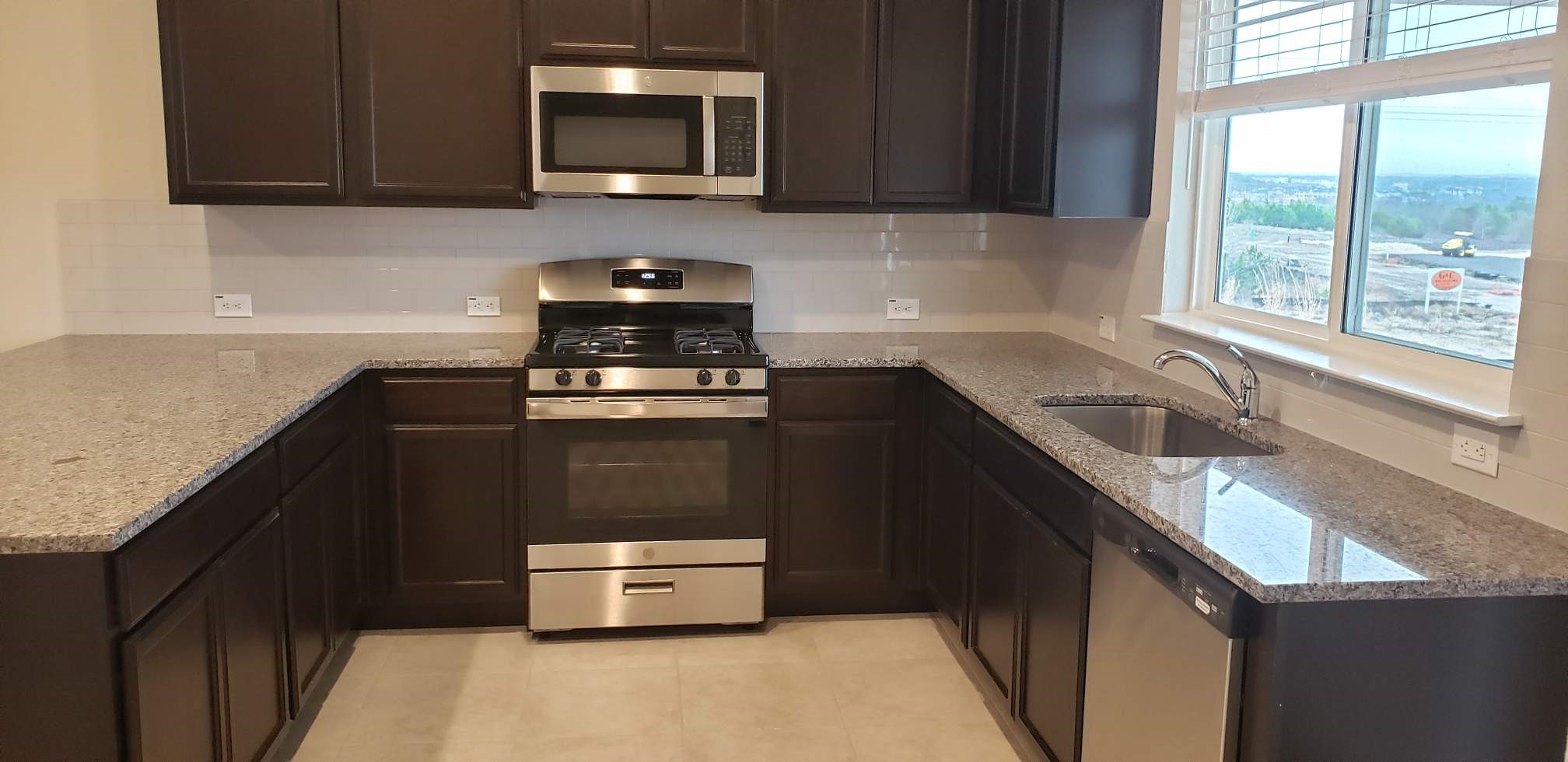 5612 Respinto Drive Austin, TX 78747 - Photo 11 of 23 a kitchen with stainless steel appliances granite countertop a sink stove and microwave