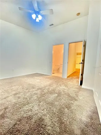 a view of an empty room with a chandelier fan