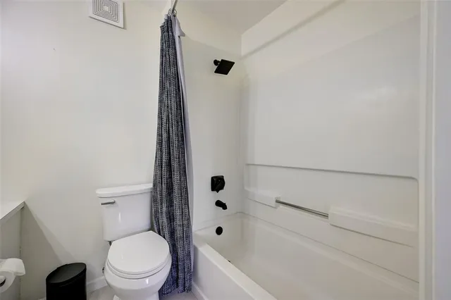 a bathroom with a toilet a white tub and a shower