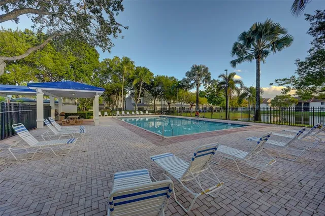 a view of a patio with a table and chairs under an umbrella with palm trees