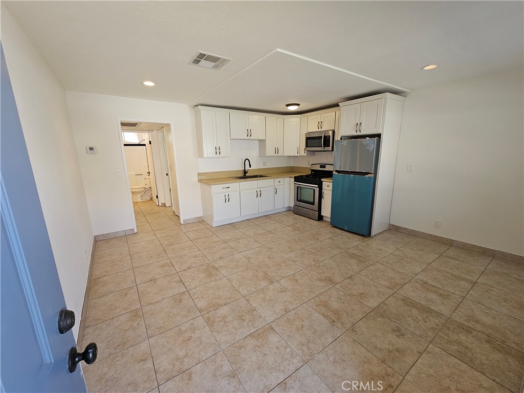 10037 Samoa Avenue, Unit 6 Tujunga, CA 91042 - Photo 1 of 7 a large white kitchen with a sink a counter top space stainless steel appliances and cabinets