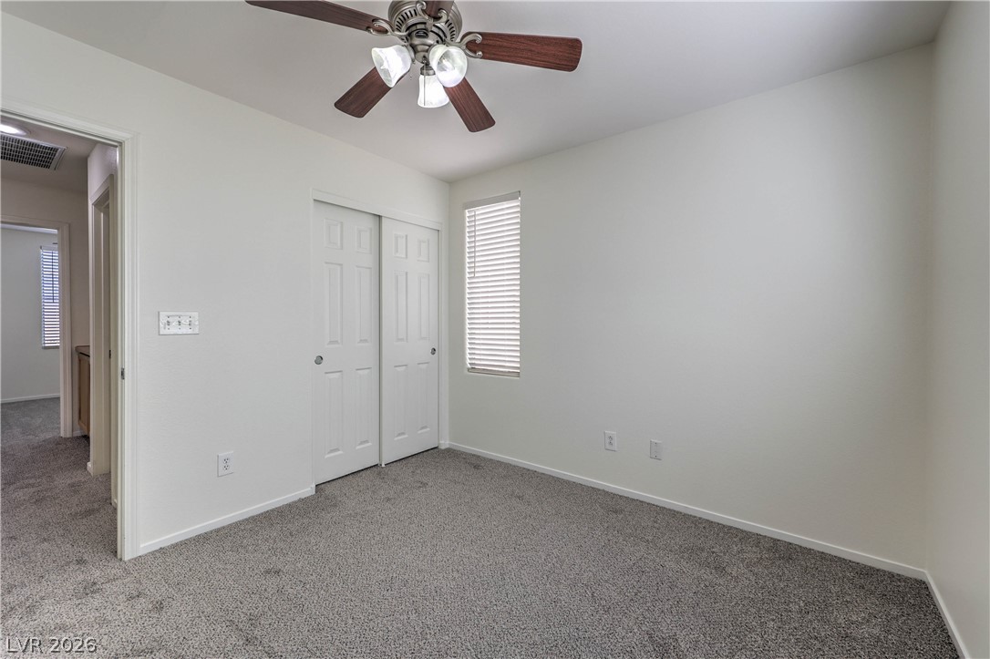 10939 Paradise Road Henderson, NV 89052 - Photo 31 of 36 A well-lit bedroom features plush carpeting and a convenient closet, awaiting personal touches.