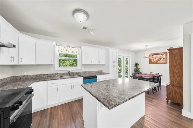 a kitchen with granite countertop a stove sink and cabinets